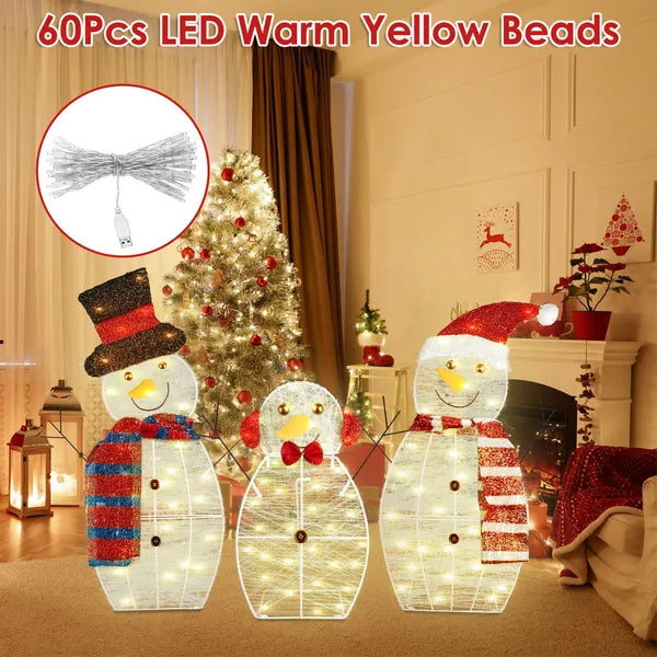 Three LED-lit snowman family yard decorations with warm yellow lights in a cozy living room