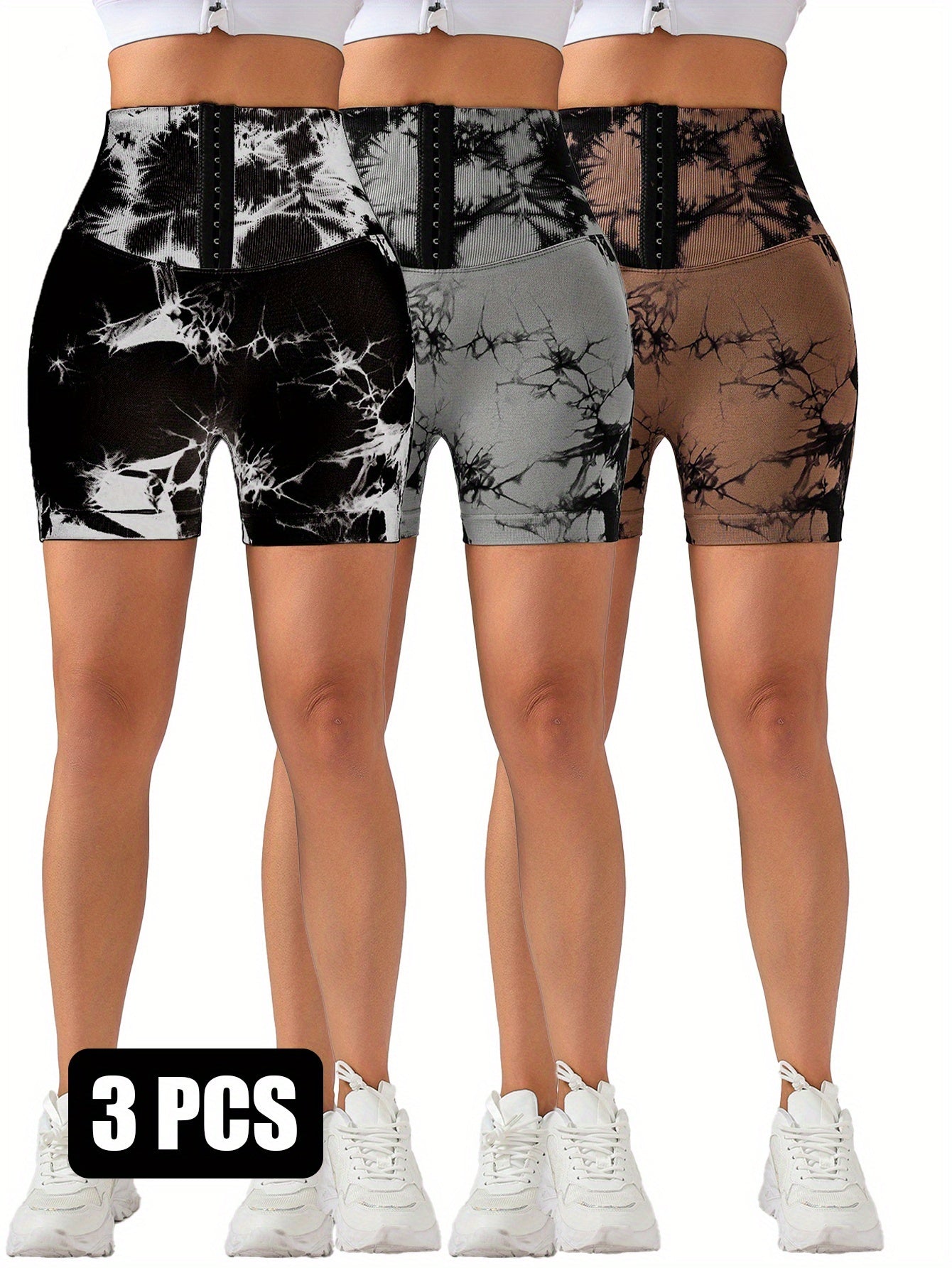 Three pairs of high-waisted tie-dye scrunch butt lifting shorts in black, grey, and brown with hook front and white sneakers