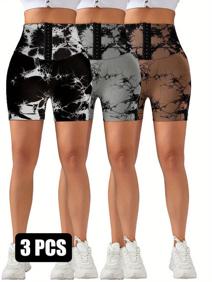 Three pairs of high-waisted tie-dye scrunch butt lifting shorts in black, grey, and brown with hook front and white sneakers