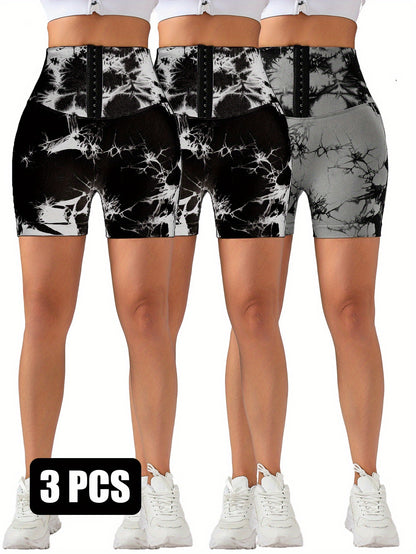 Three pairs of high-waisted tie-dye compression shorts with hook-and-eye front in black and gray shades, worn with white sneakers