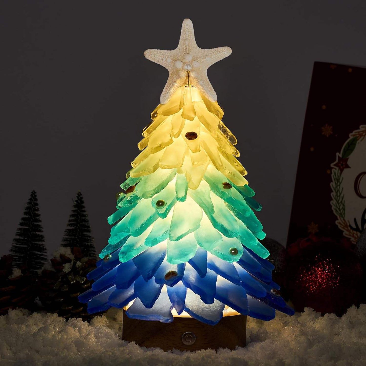 Mini LED Christmas tree ornament with blue and green sea glass shards topped with a starfish, glowing warmly