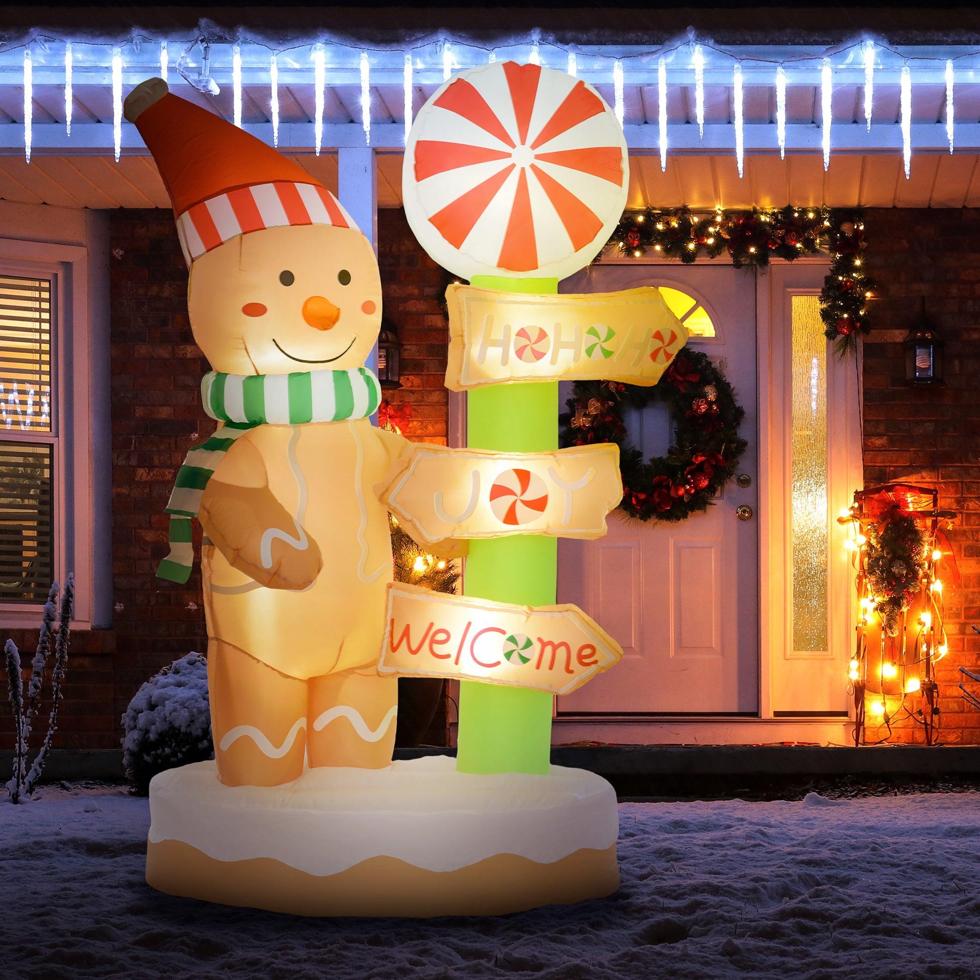 Inflatable gingerbread man decoration with striped hat and scarf, holding candy-themed holiday signs outdoors