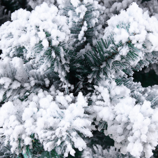 Close-up of flocked artificial Christmas tree branches covered in white snow-like flocking
