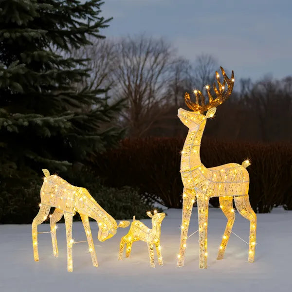 Three-piece outdoor lighted reindeer family set with warm white LED lights in snowy yard at dusk