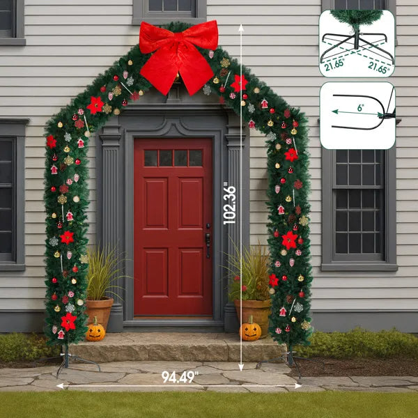 Festive artificial Christmas tree archway decorated with red bows and ornaments around a red door entrance