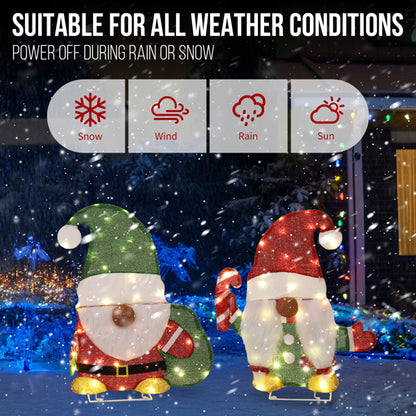 Lighted Christmas gnome decorations with candy cane and green sack in snowy outdoor winter scene