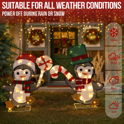 Lighted Christmas penguin decorations wearing festive hats and scarves holding candy canes on a lawn at night