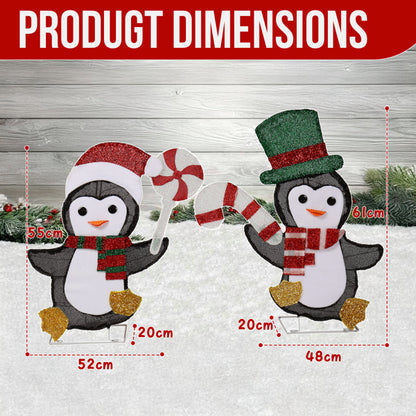 Two glittery penguin Christmas decorations with candy cane, one wearing Santa hat and scarf, the other with top hat and scarf