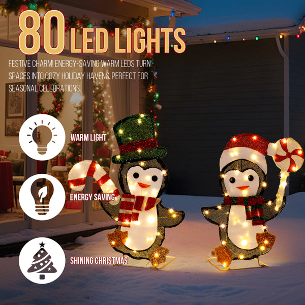 Outdoor Christmas decoration with two LED lit penguins holding candy canes in snow at night