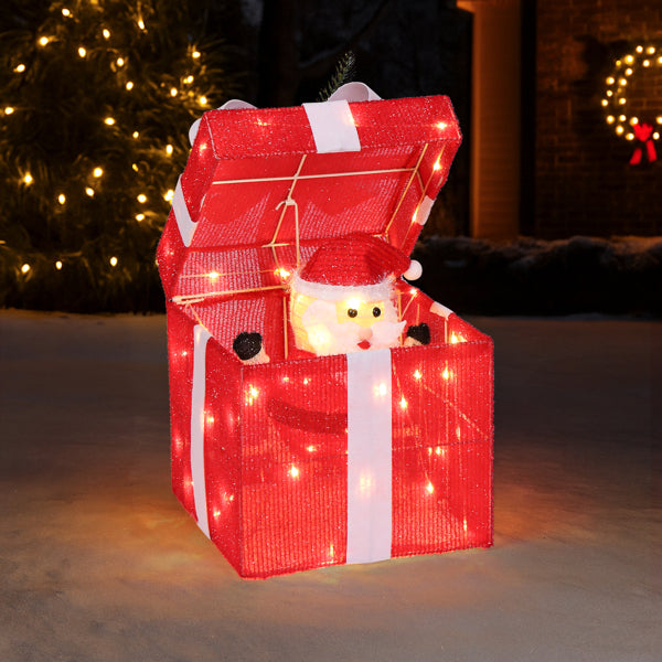 Motorized light-up red gift box decoration with Santa figure popping up, illuminated with 60 LED lights outdoors at night