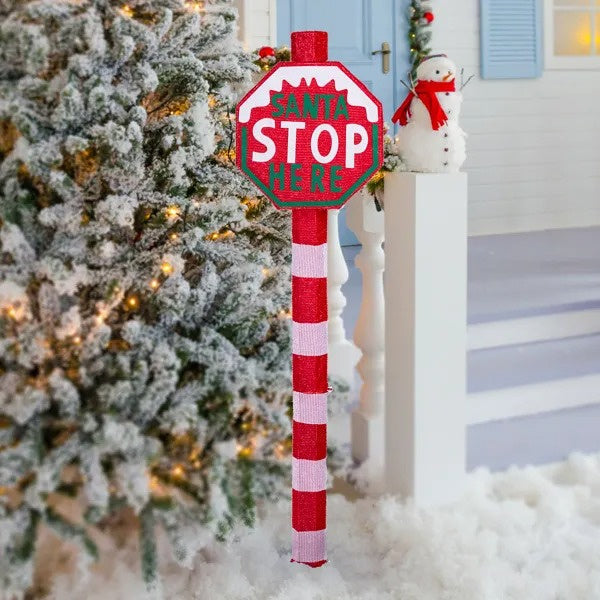 Lighted Santa Stop Here sign with 70 LED lights, red and white striped pole next to snowy Christmas tree and snowman decor