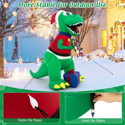6ft inflatable green Christmas dinosaur yard decoration with LED lights, Santa outfit, and gift box in snowy yard