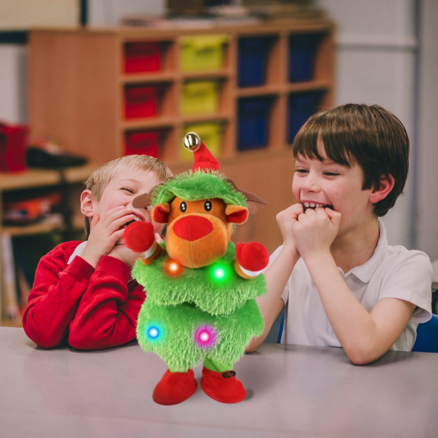 Two children laughing at a talking, dancing plush toy dressed as a Christmas tree with colorful lights