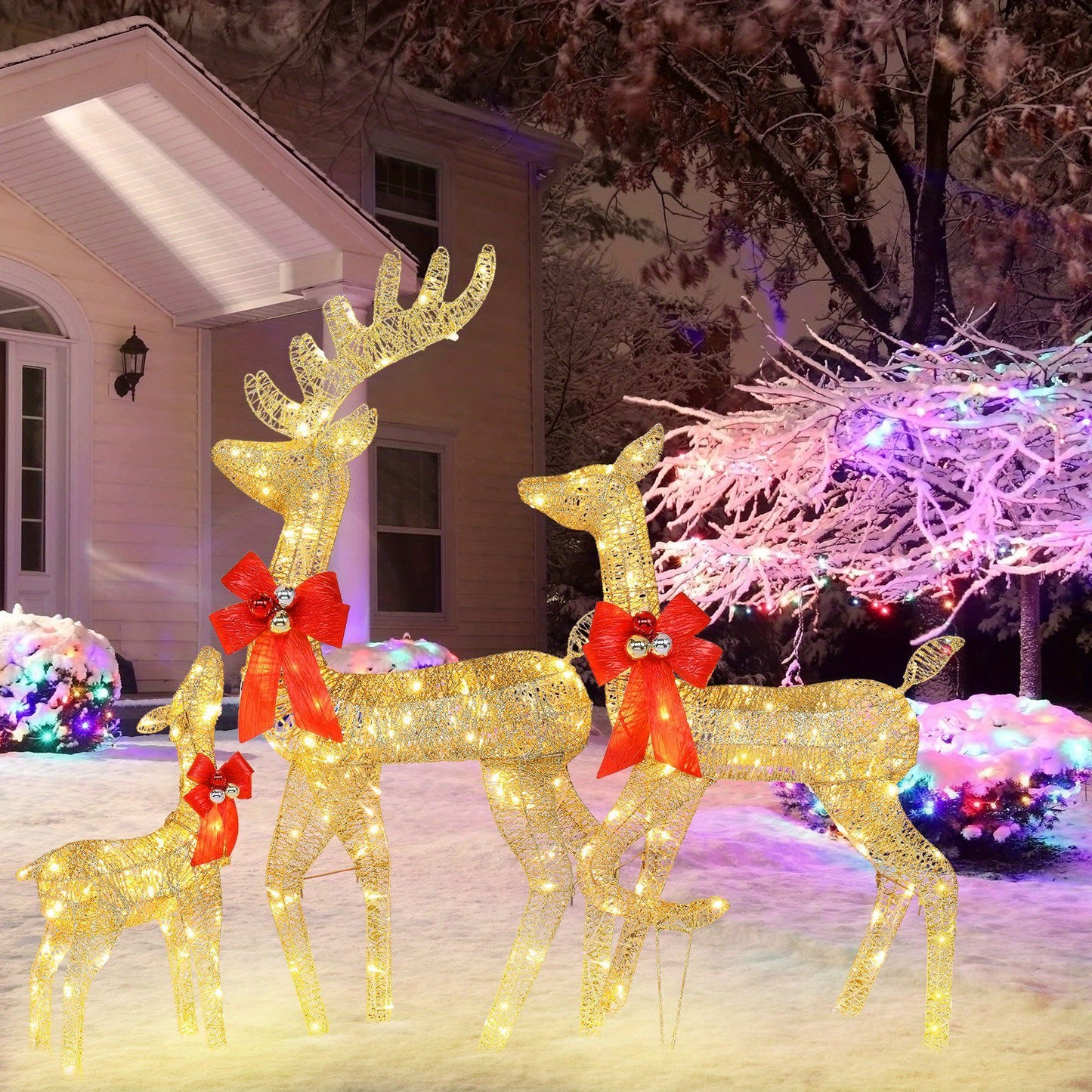 Outdoor Christmas scene with golden light-up reindeer family decoration wearing red bows in snowy yard