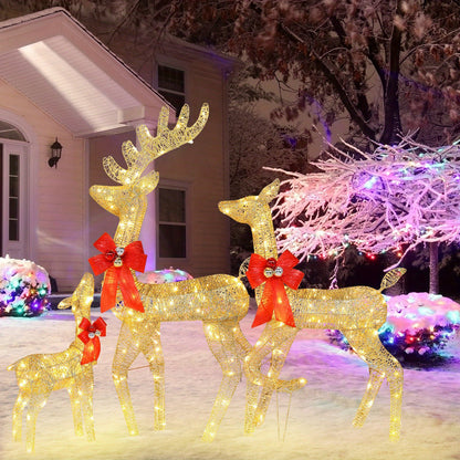 Outdoor Christmas scene with golden light-up reindeer family decoration wearing red bows in snowy yard