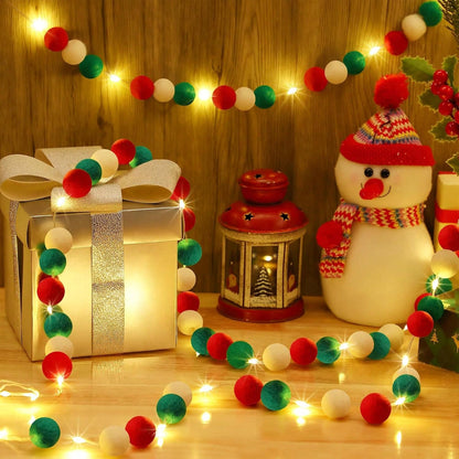 Christmas scene with red, green, white pom pom garland, glowing gift box, snowman, and lantern