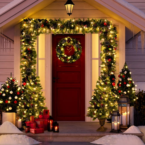 Festively decorated porch with pre-lit green garland, wreath, small Christmas trees, red door, and candles