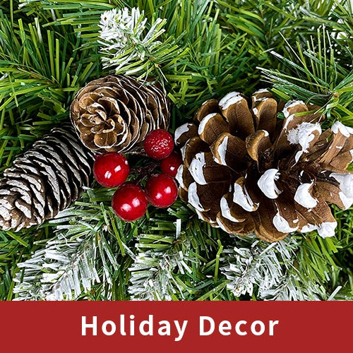 Green artificial pine branches decorated with snow-dusted pine cones and red berries for holiday decor