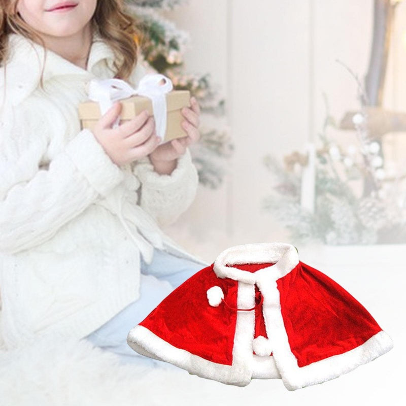 Child holding gift box near Christmas tree with red velvet fur-trimmed kids cape costume