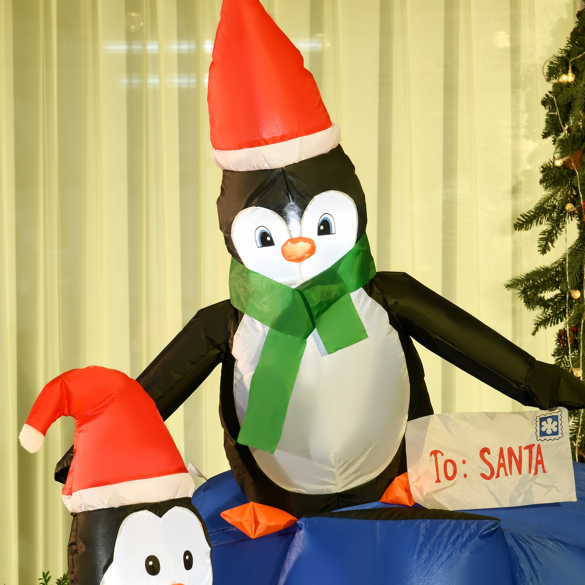 Inflatable Christmas penguins with Santa hats, one holding a letter addressed To: Santa