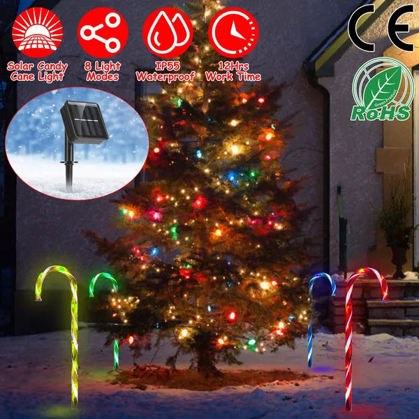 Multicolor solar candy cane stake lights illuminating snowy yard with decorated Christmas tree at night