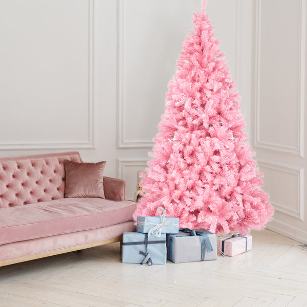 6ft pink PVC Christmas tree with blue and pink wrapped gifts beside a pink velvet sofa in a bright white room