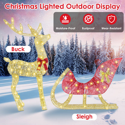 Lighted Christmas outdoor display featuring illuminated golden reindeer with red bow and matching red sleigh in snowy forest
