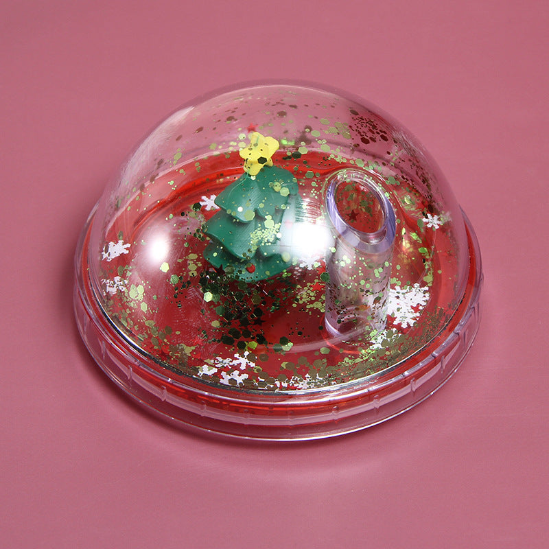 Christmas tree 3D figurine dome lid with gold and white snowflake glitter on red base, pink background