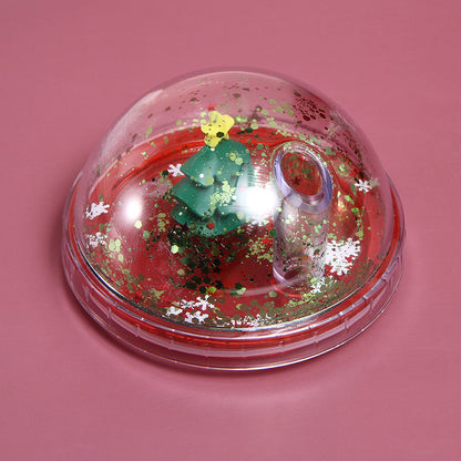 Christmas tree 3D figurine dome lid with gold and white snowflake glitter on red base, pink background