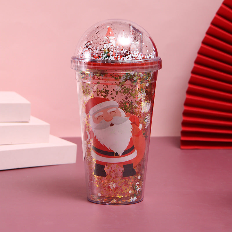 Christmas-themed water cup with Santa Claus design and glitter-filled dome lid on pink background