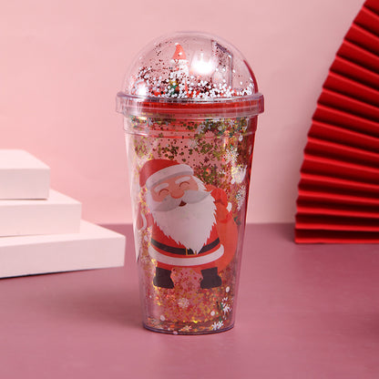 Christmas-themed water cup with Santa Claus design and glitter-filled dome lid on pink background