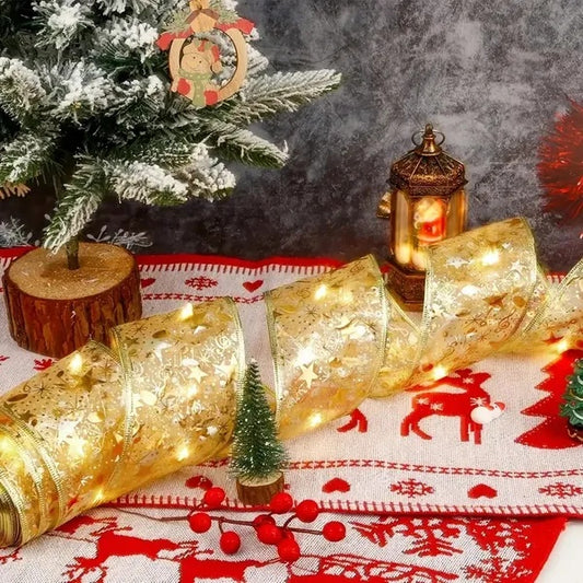 Christmas scene with snow-dusted pine tree, gold star-patterned ribbon with lights, lantern, and festive red decorations