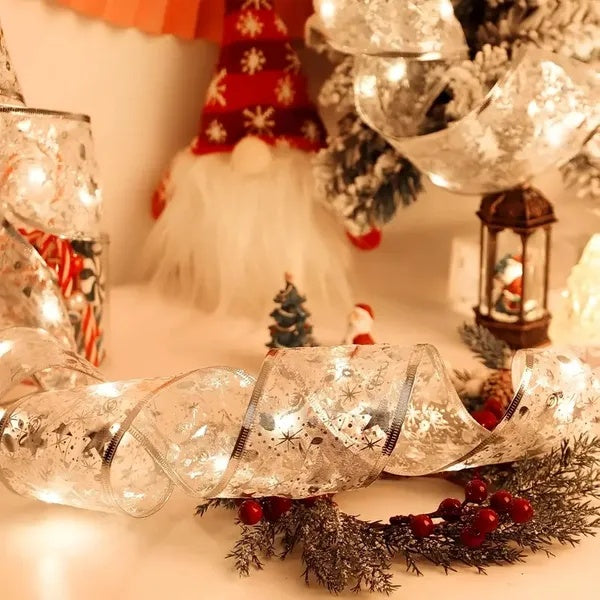 Silvery ribbon with warm white Christmas lights, red berries, pine branches, and holiday figurines