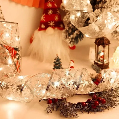 Silvery ribbon with warm white Christmas lights, red berries, pine branches, and holiday figurines