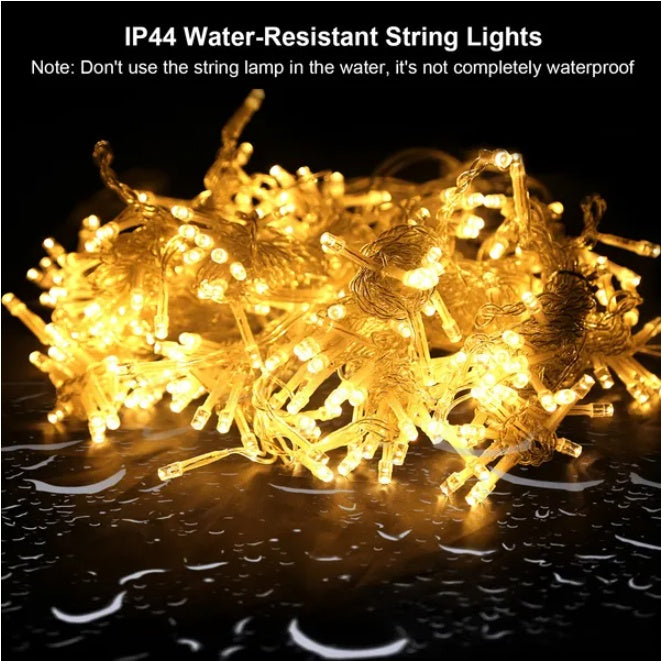 Warm white IP44 water-resistant LED string lights glowing on wet surface with caution text