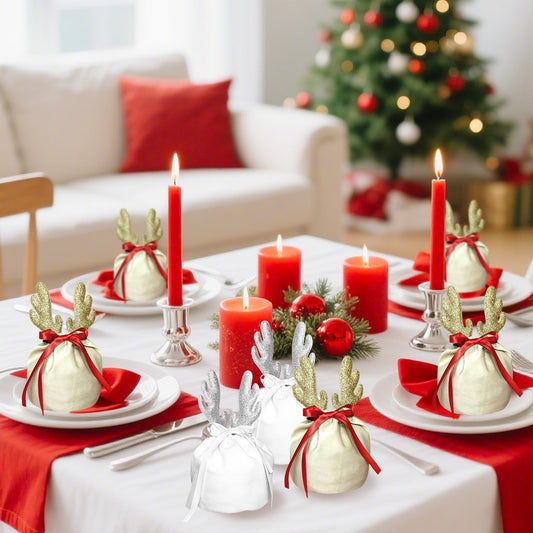 Christmas dining table with red candles and fabric gift bags decorated with golden and silver reindeer antlers