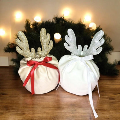 Christmas gift bags in khaki and white fabric with glittery reindeer antler decorations and ribbon bows