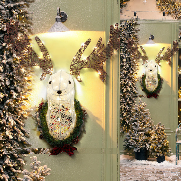 Lighted white reindeer head wall decor with warm white LED lights, wreath, and snowy Christmas trees