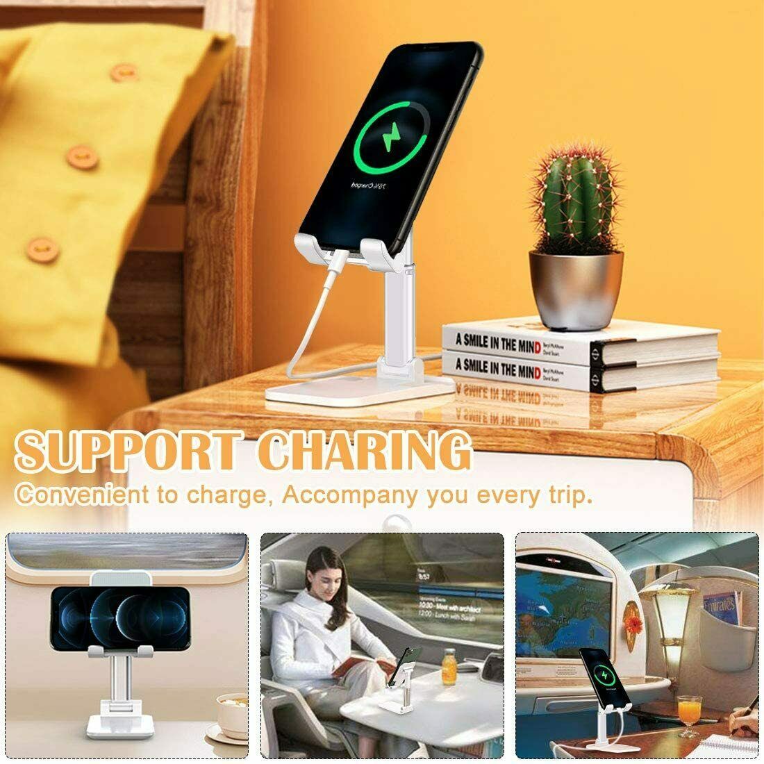 White foldable adjustable phone stand on wooden table with smartphone charging, cactus, books, and travel scenes
