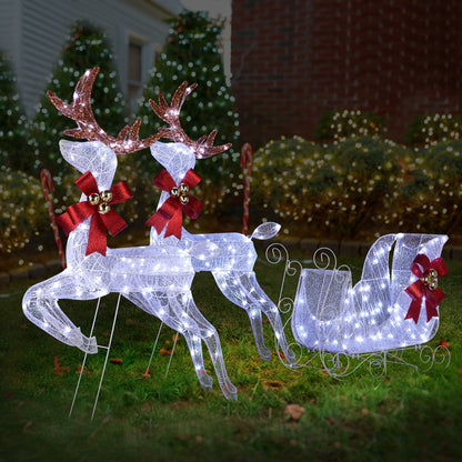 White LED reindeer and sleigh Christmas yard decoration with red bows and bells on green grass