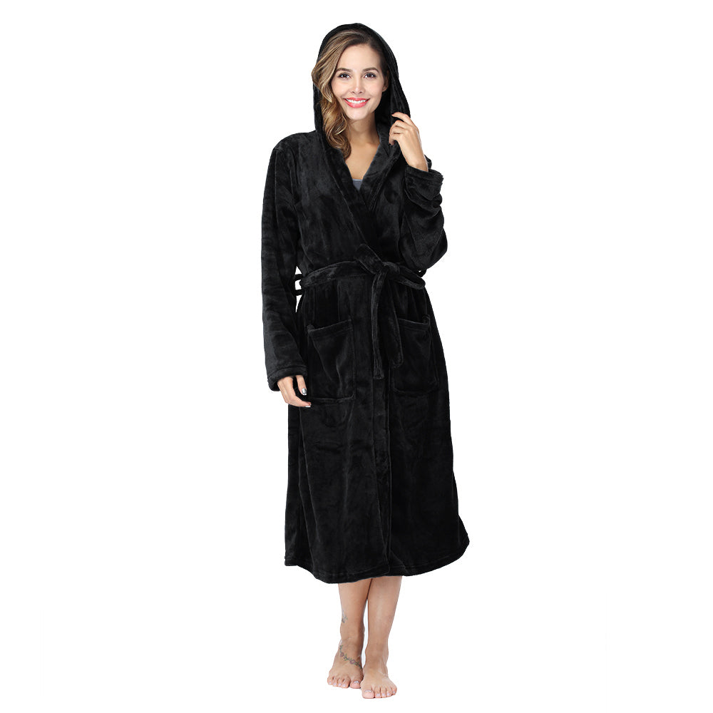 Woman wearing black plush fleece hooded robe with pockets and belt, standing barefoot